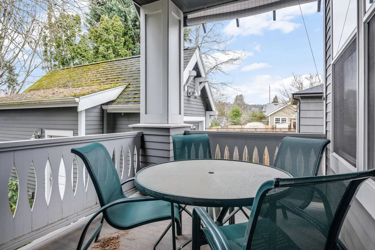 A peaceful exterior shot featuring a round table with green chairs and a balcony railing, creating a cozy nook ideal for meals, reading, or conversation. The tranquil setting reinforces the theme of relaxed, flexible outdoor living spaces that expand as the seasons allow.