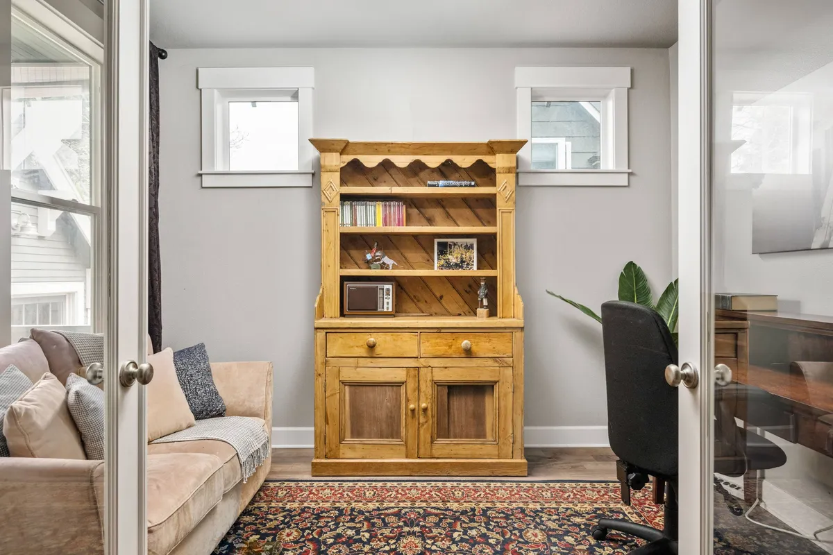 A cozy interior area with a wooden cabinet, a soft sofa, and a textured rug. The space is inviting and designed for comfort, making it conducive to reading, working, or relaxing in a tranquil atmosphere.